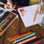 Kredki akwarelowe: jak ich używać, by uzyskać efekt malarski, a nie „kolorowankę” Kolorowe kredki akwarelowe i szkicownik na artystycznym biurku