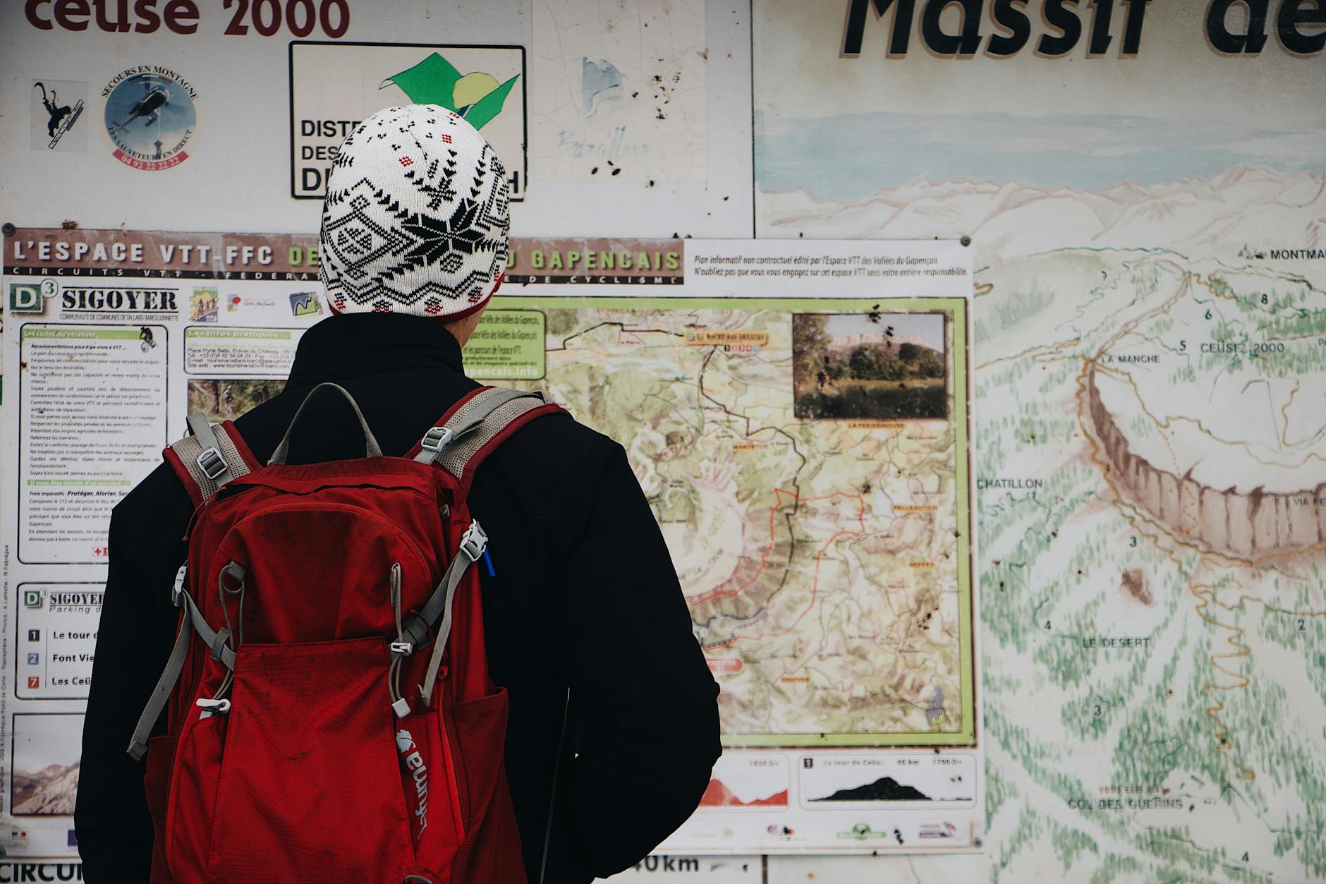 Uczeń z czerwonym plecakiem analizuje górską mapę szlaku
