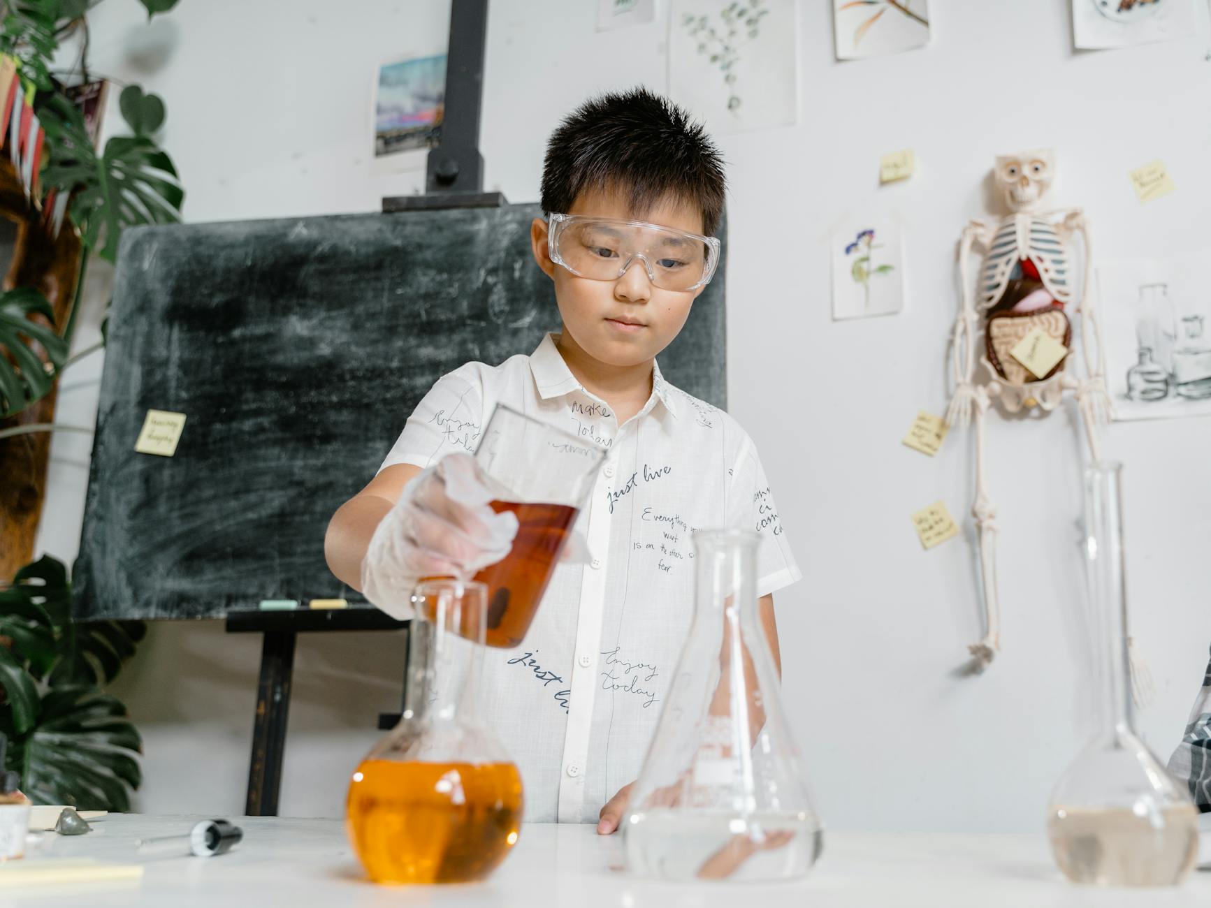 Uczeń w okularach ochronnych wykonuje doświadczenie chemiczne w klasie