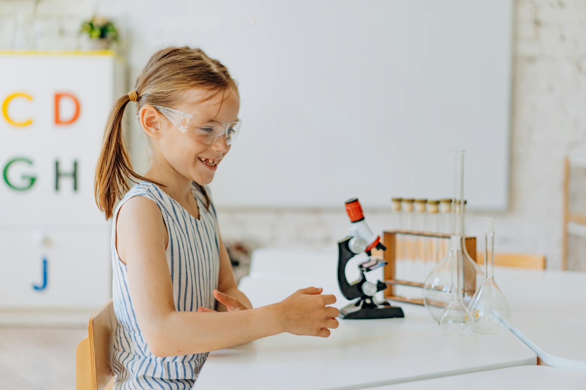 Uśmiechnięta uczennica obserwuje próbki w mikroskopie na lekcji chemii