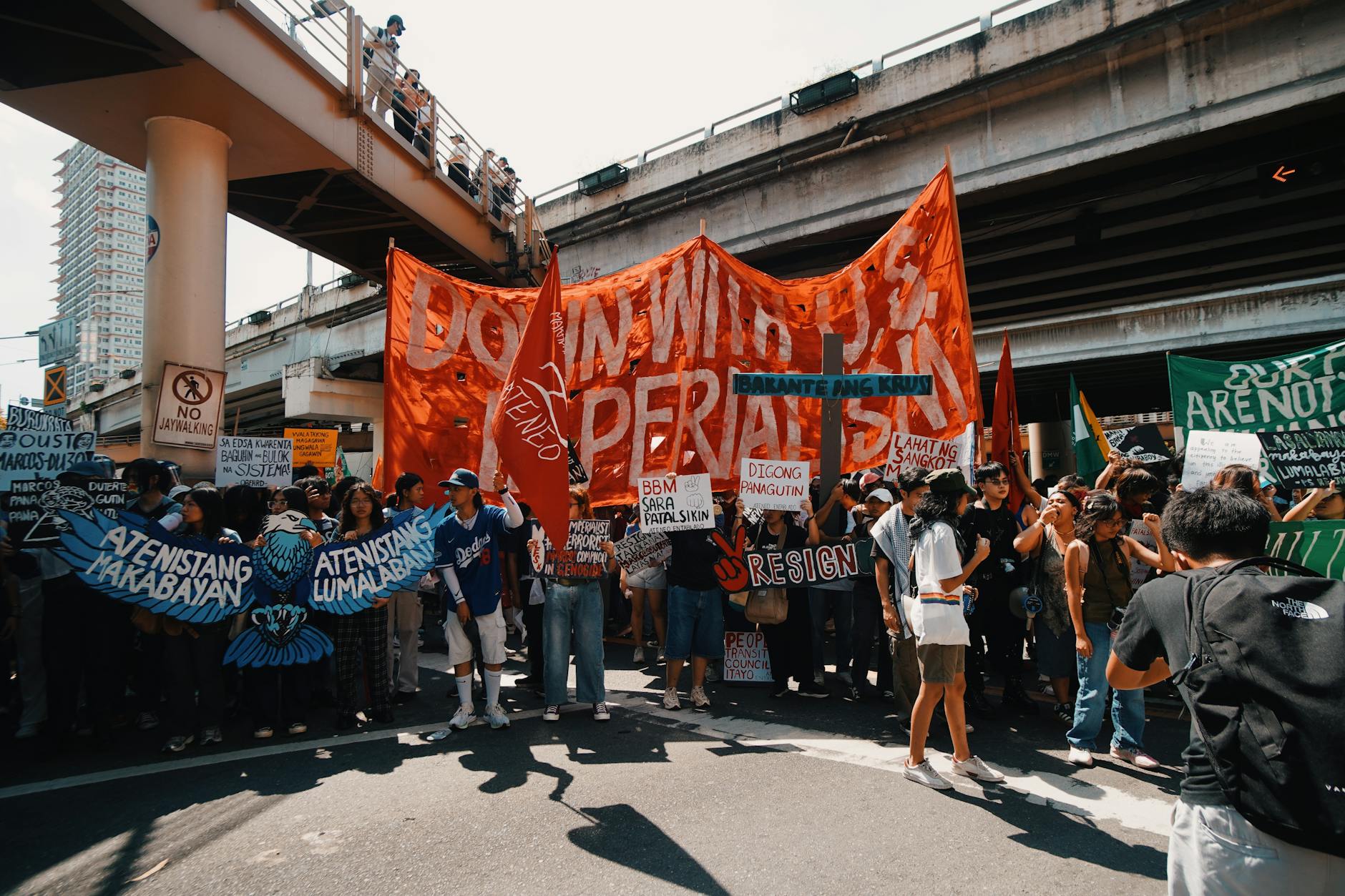 Tłum demonstrantów z transparentami pod miejskim wiaduktem