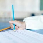 Dziecko pisze kolorowymi kredkami w klasie podczas lekcji języka polskiego