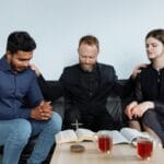 Czym jest miłość w etyce i w religii: eros, philia, agape w jasnym ujęciu Grupa dorosłych modli się i czyta Biblię przy stole w domu