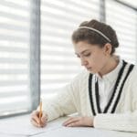 Czym różni się parafraza od cytatu i jak je stosować, by nie popełnić plagiatu? Uczeń pisze egzamin w jasnej sali lekcyjnej