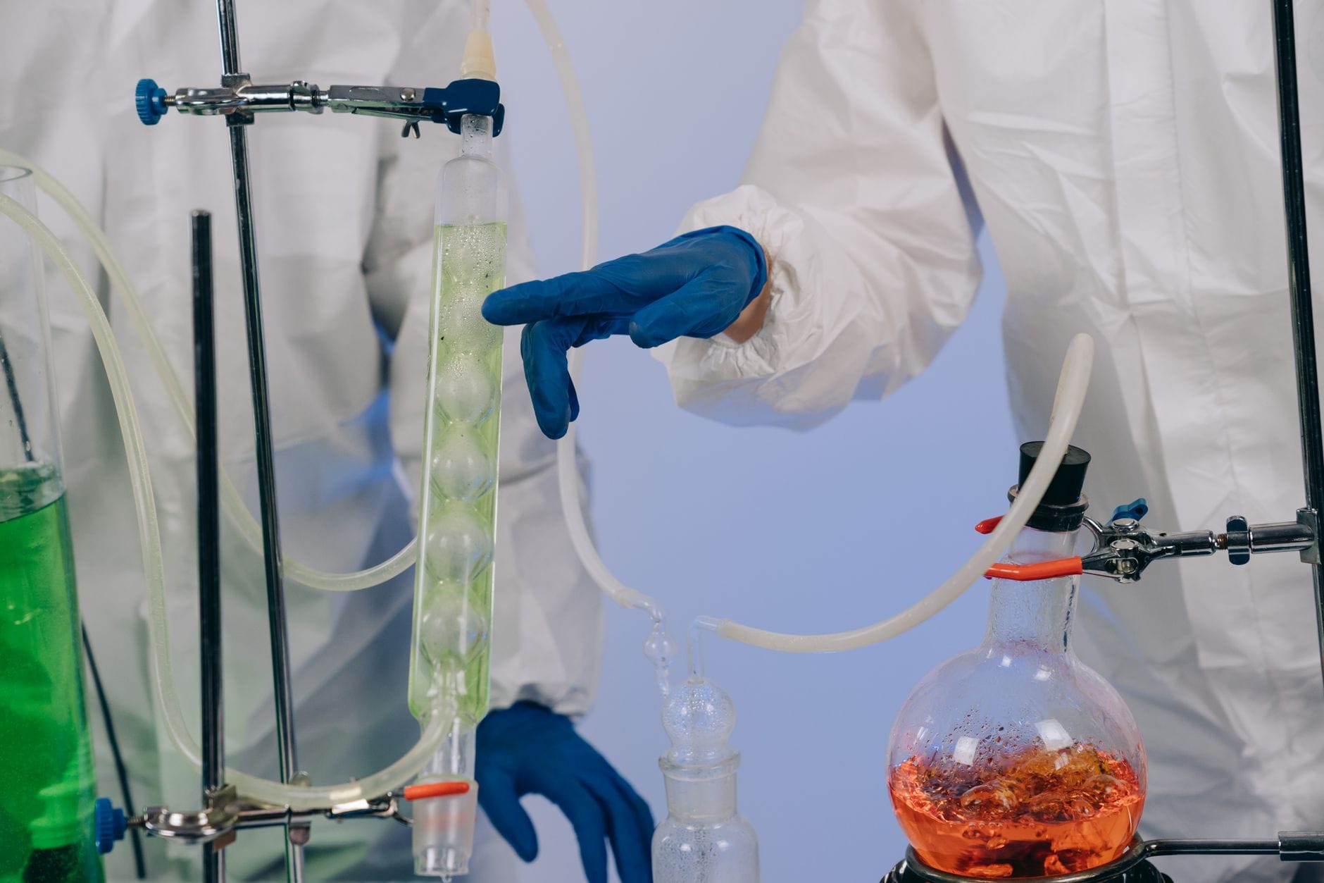 Naukowcy w odzieży ochronnej podczas eksperymentów chemicznych w laboratorium