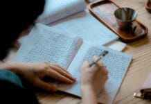Osoba zapisująca azjatyckie znaki w notesie