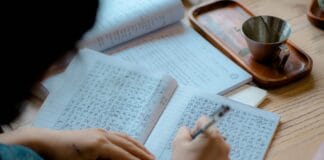 Osoba zapisująca azjatyckie znaki w notesie
