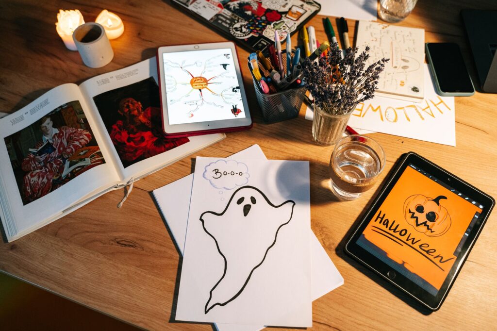 Halloweenowe rysunki i tablety na drewnianym stole do prac plastycznych